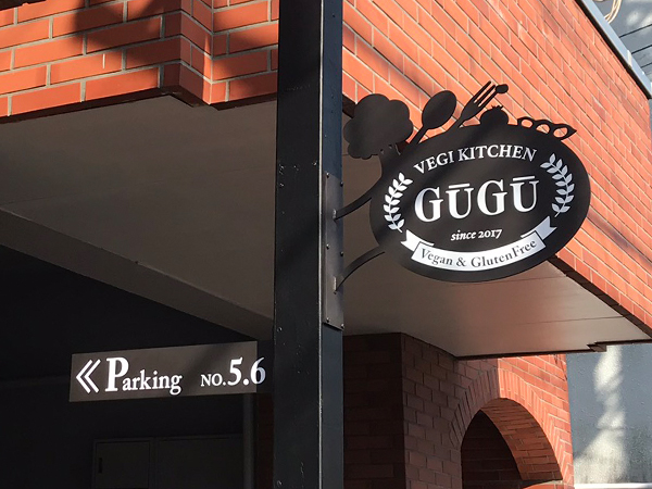 料理店のイメージを切り抜いた黒い鉄製の袖看板と駐車場を案内する看板