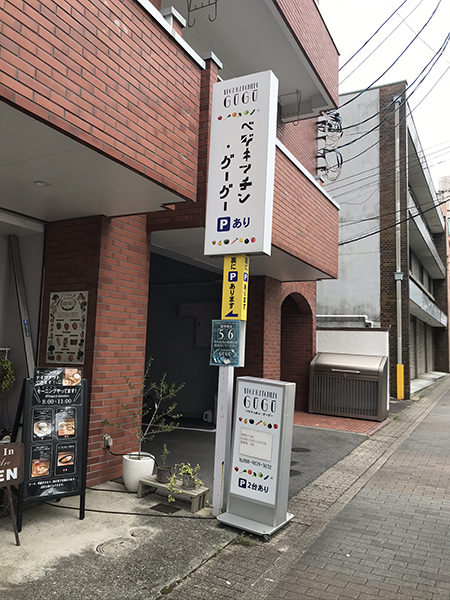 建物前の支柱の上の方に白い大きな看板が付いている様子