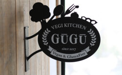 木の壁に取り付けられた野菜のシルエットが付いた袖看板