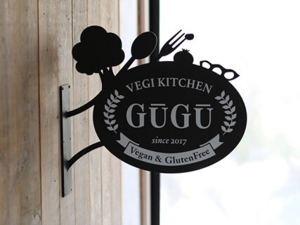 木の壁に取り付けられた野菜のシルエットが付いた袖看板